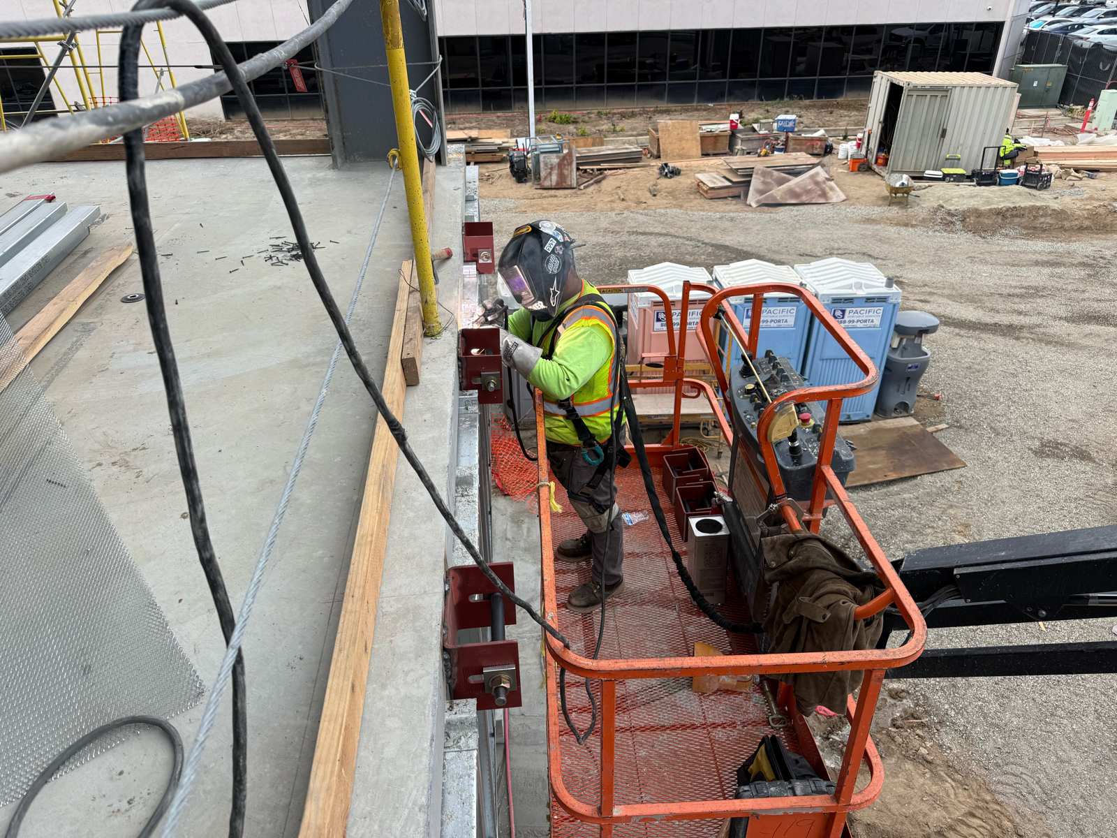 Inspector-observed field welding of curtain wall anchor clips from an aerial lift